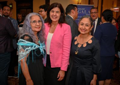 The image shows a group of women posing for a photo at the MALDEF Chicago Gala 2024. They are standing on stairs and smiling. The photo captures a moment of friendship and social gathering.